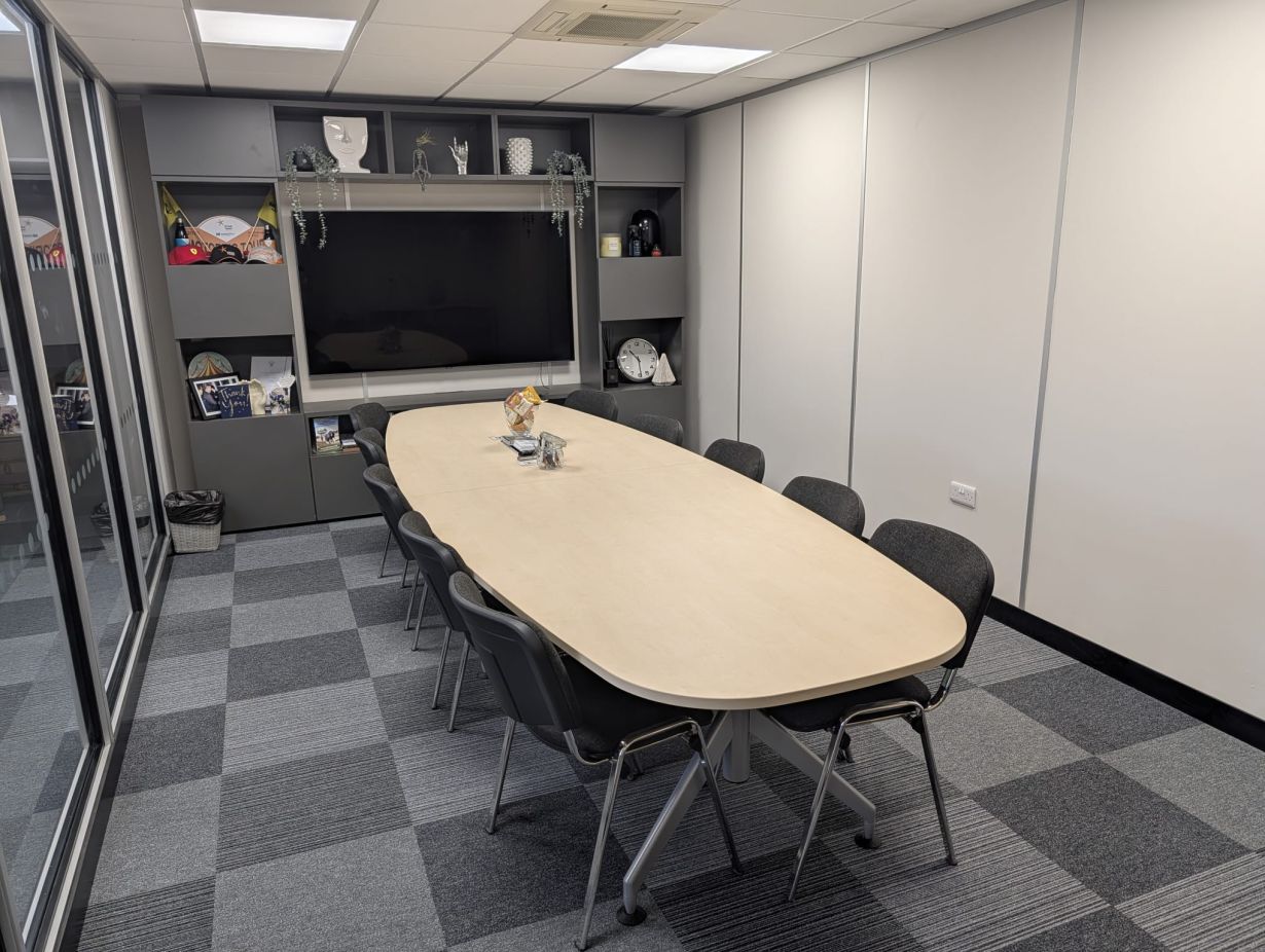 Functional and well-equipped meeting room in Harlaxton House with a large wall display of business achievements, designed for effective presentations and strategic discussions in a professional setting.