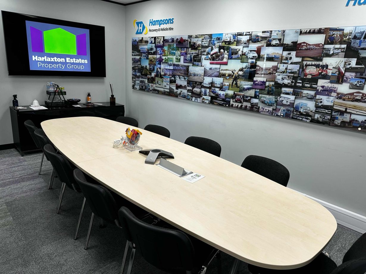 Functional and well-equipped meeting room in Harlaxton House with a large wall display of business achievements, designed for effective presentations and strategic discussions in a professional setting.